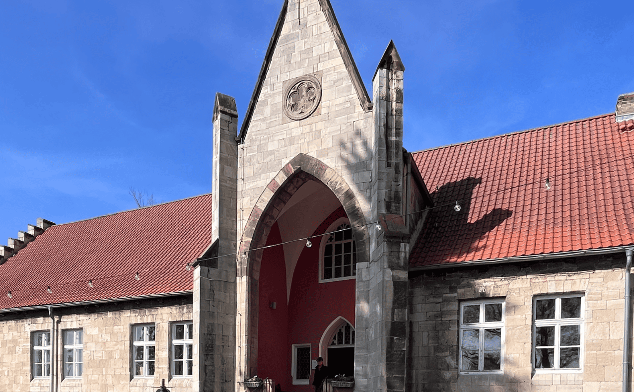DSW-Mitgliedervertreterfahrt-Sekt-und-Wein-Manufaktur-BB-07 Historische Kirche in Naumburg mit gotischer Architektur und rotem Ziegeldach, unter blauem Himmel, im Rahmen der Weinregion Naumburg.