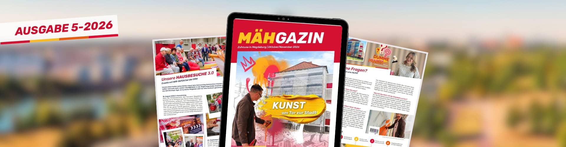 MÄHGAZIN Ausgabe 05-2026 mit Kunstthema, umgeben von gedruckten Ausgaben, im Hintergrund eine Stadtlandschaft bei Sonnenuntergang.